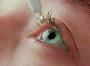 tip of eye dropper dripping drop into eye